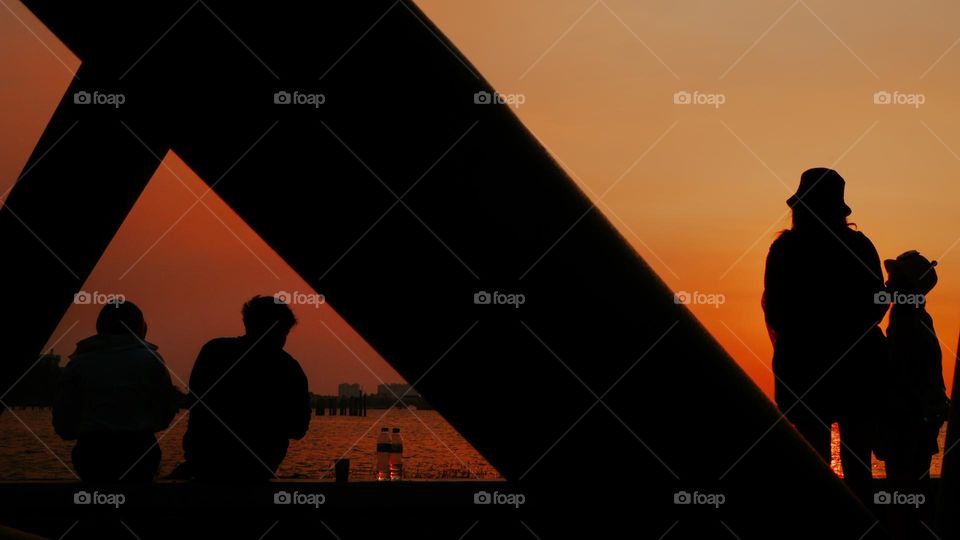 Silhouette portrait of a visitor on a beach in the evening against a sky background with golden light, waiting and enjoying the sunset on the beach. natural light.