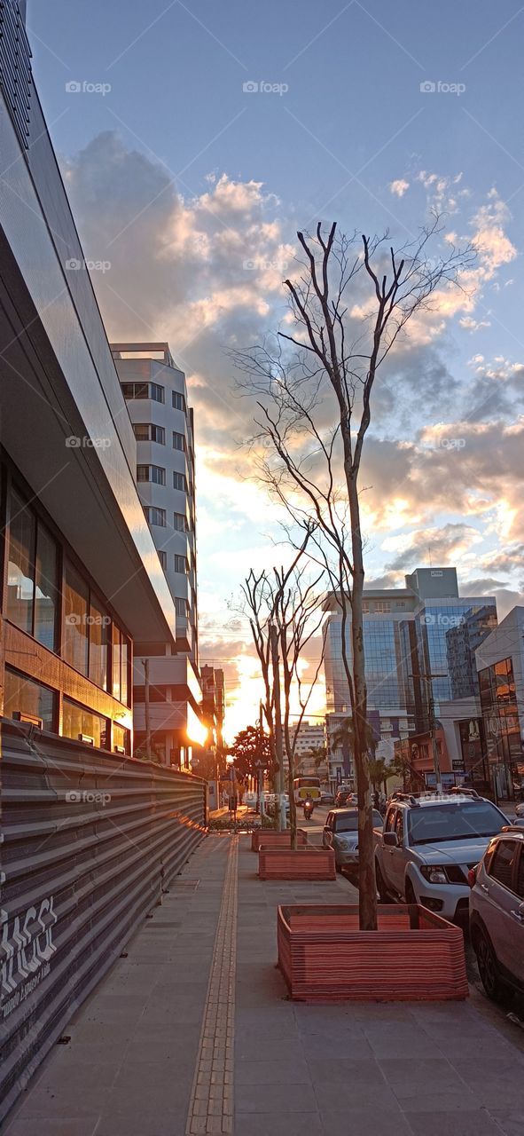 Streets, cars and buildings in the city at sunset