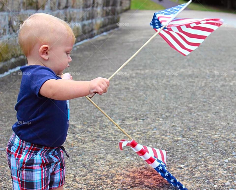 Baby Patriot . Baby boy holding two American flags. 