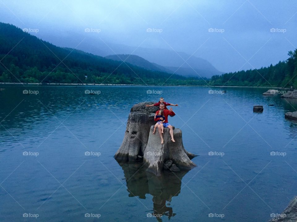 Daddy and kids on a tree stumb in the lake