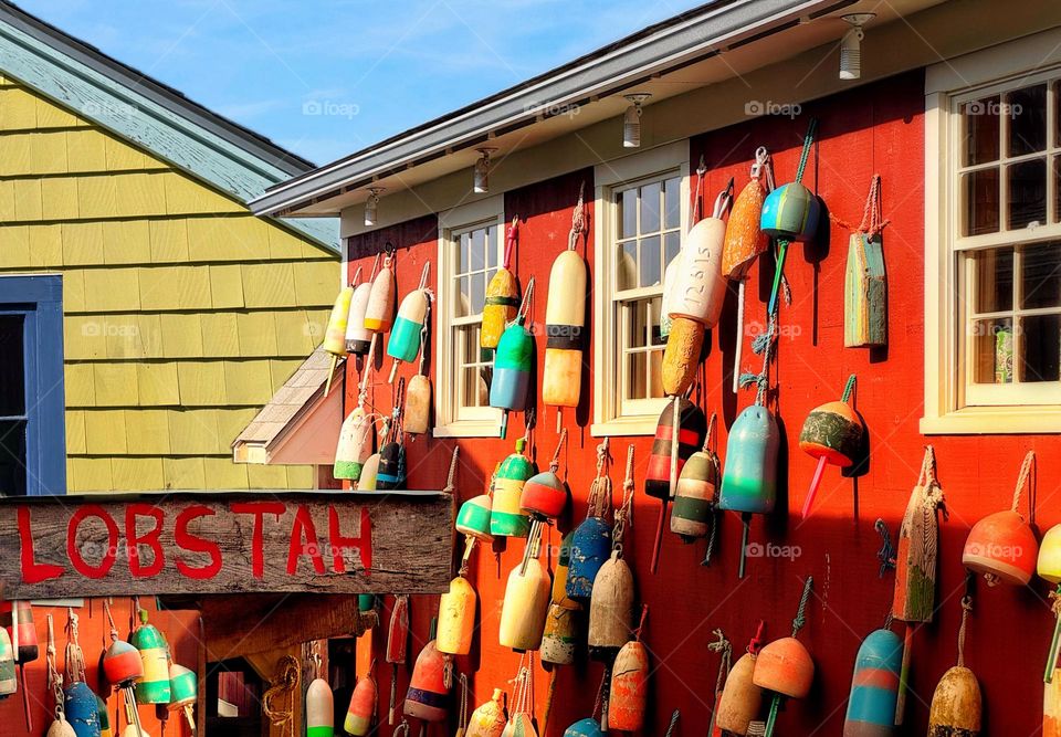 Lobster buoys on a building in Maine with a sign reading ‘lobstahs’ mimicking Maine accent 