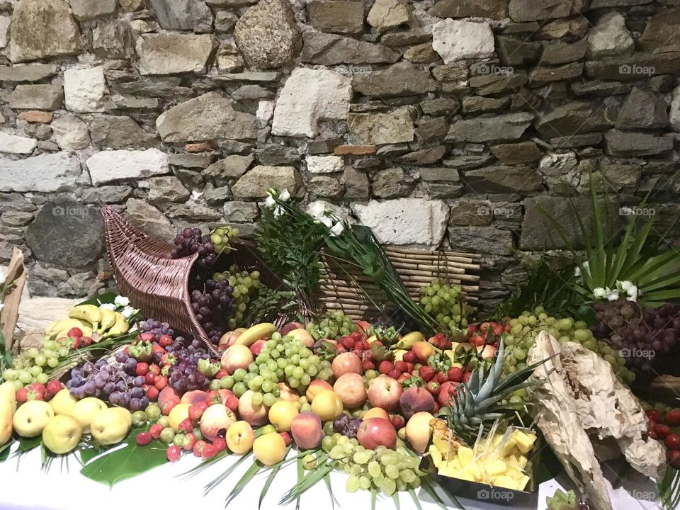 Fruits on table by stone wall 