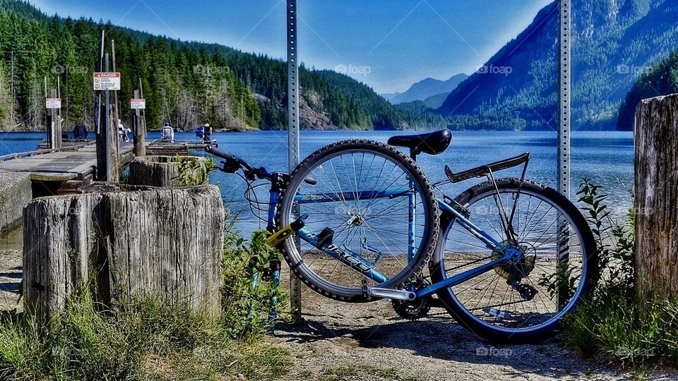 Solitary single bike bicycle, wheel dismantled and locked to post at beautiful glacial lake in British Columbia Canada