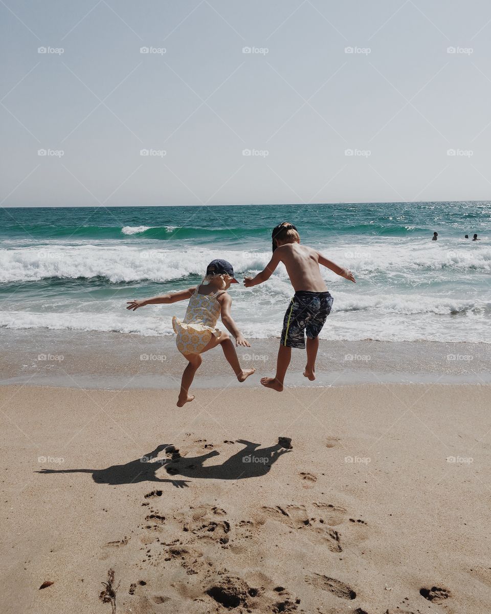 Kids jumping at the beach. 