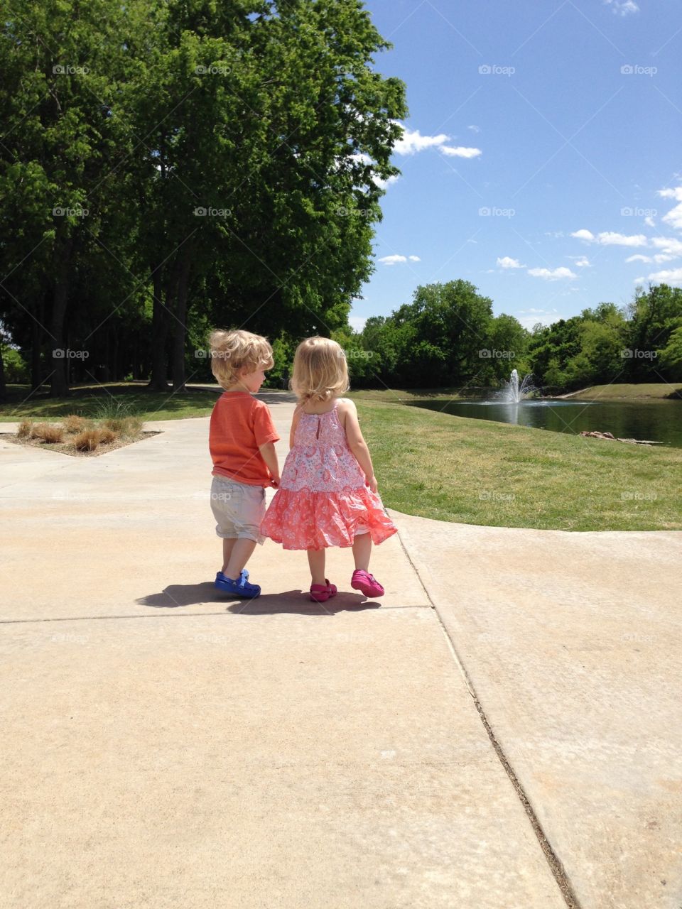 Twins looking at pond. Twins at the park