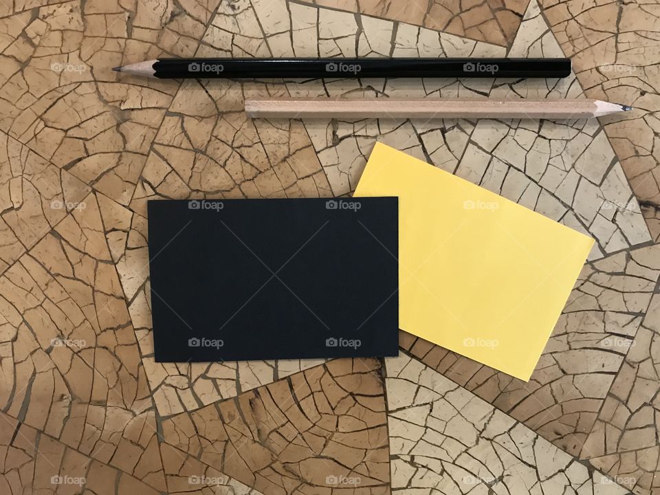 black and yellow notepad with black and brown pencils put on beautiful geometry pattern desk
