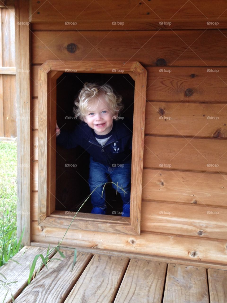 Toddler in dog house. Peek a boo