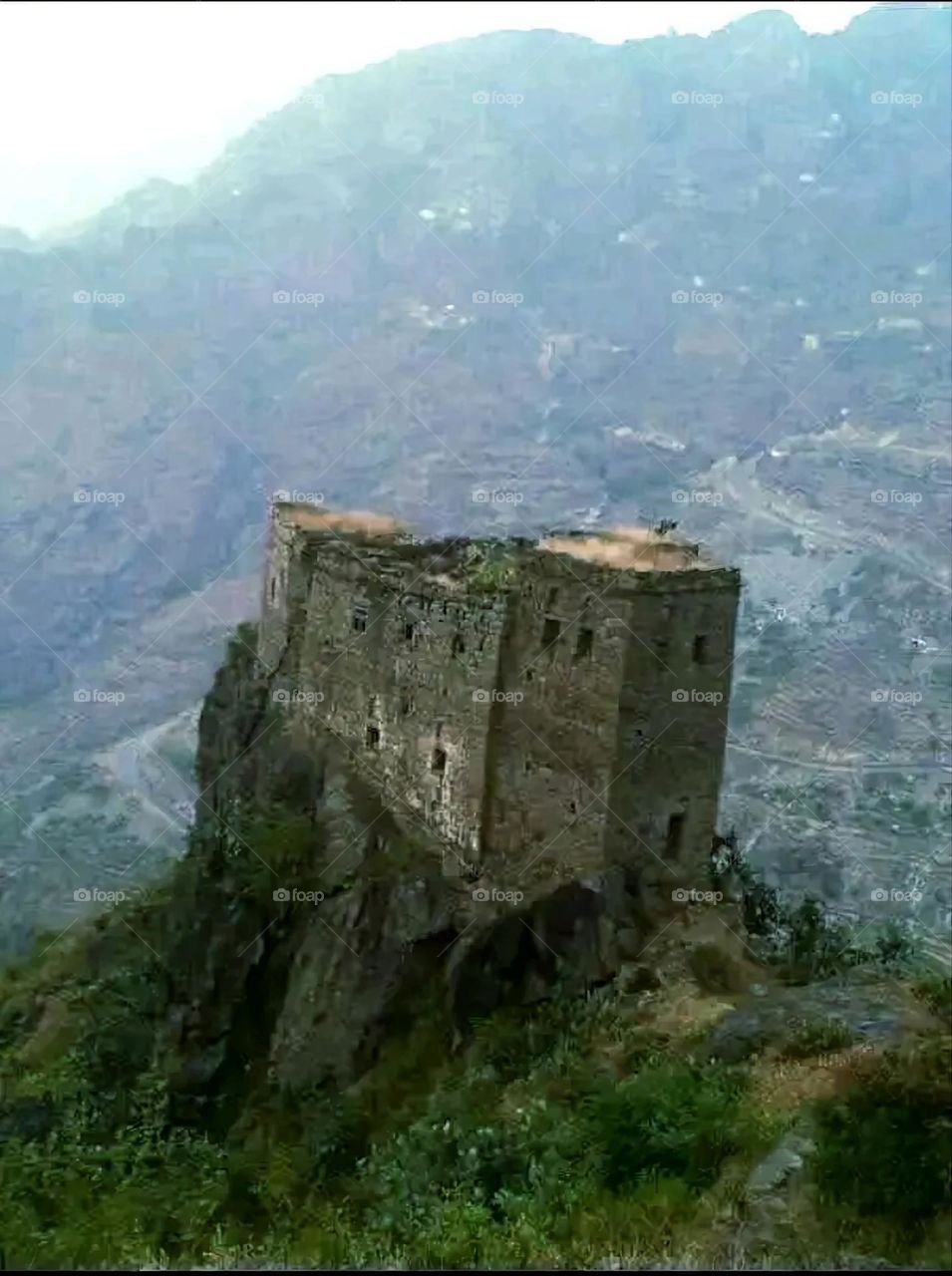 The image embodies a natural natural plate of the mountains of nature, where green agricultural stands are graded on the slopes as if they were lines of a poem, which fog harmoniously wrapped, and clouds hugged them in the mountain knife and the whis