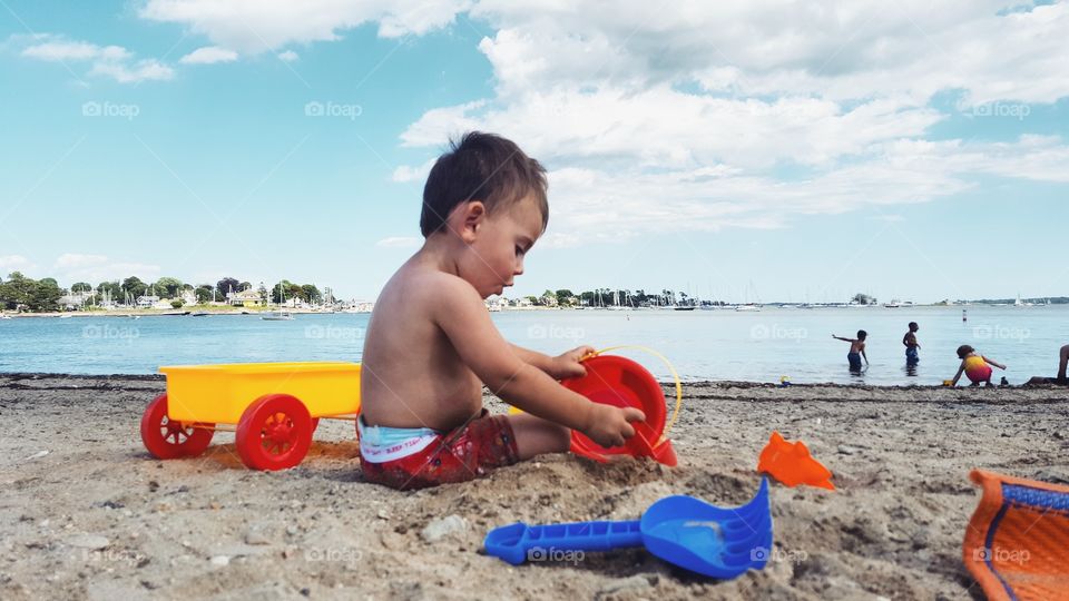 Boy playing with toy on sand near beach