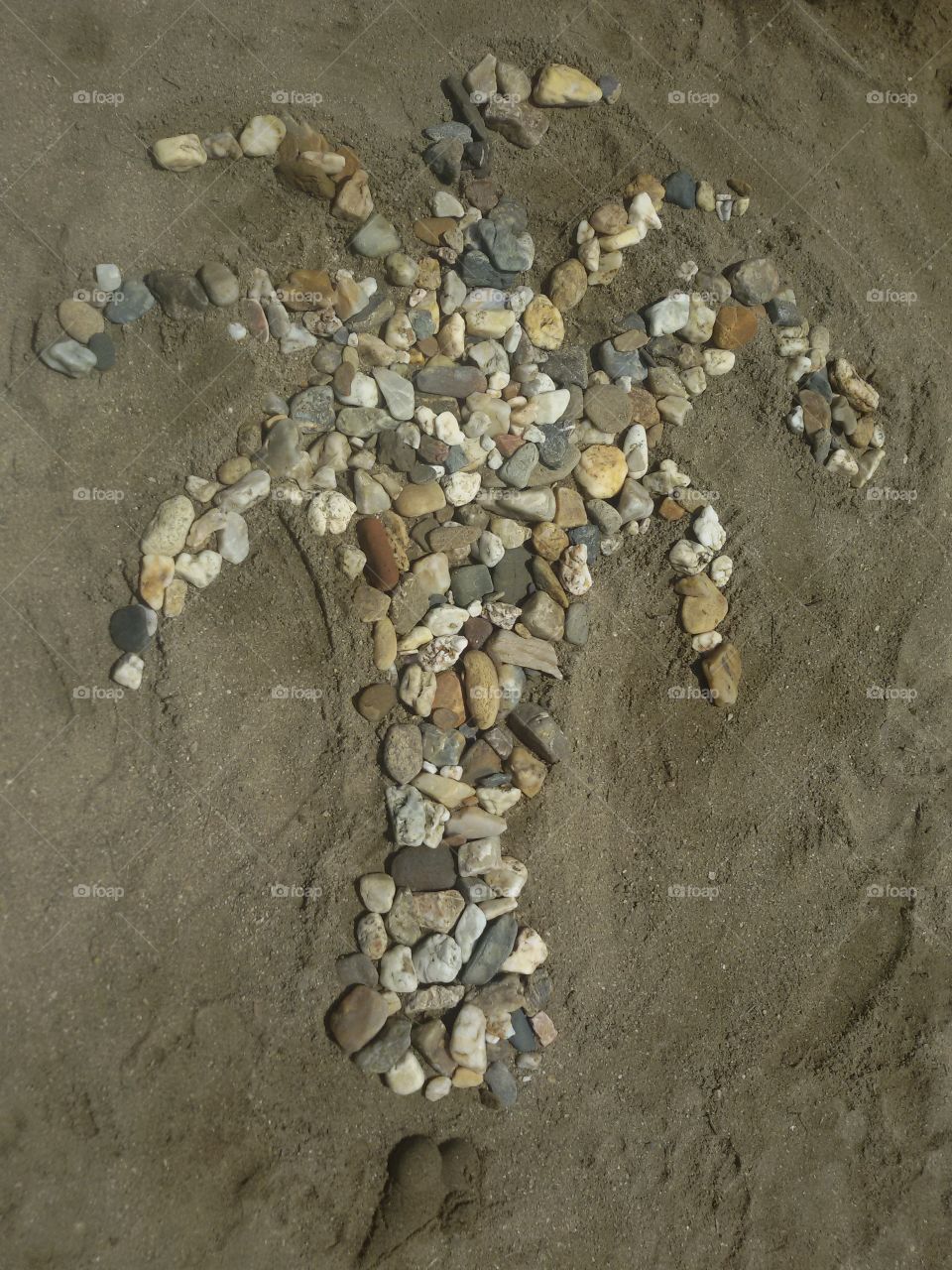 Palm tree made of rocks. Made on the sand beach