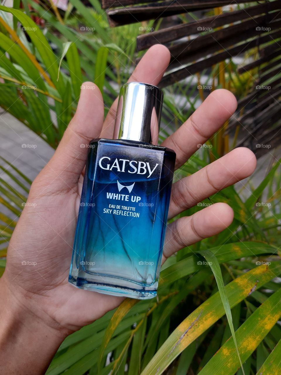 A blue parfume bottle in a hand. Parfum is a must for men and women in terms of fashion.