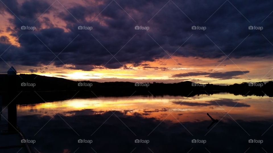 dark Sunset with dramatic clouds reflected in lake