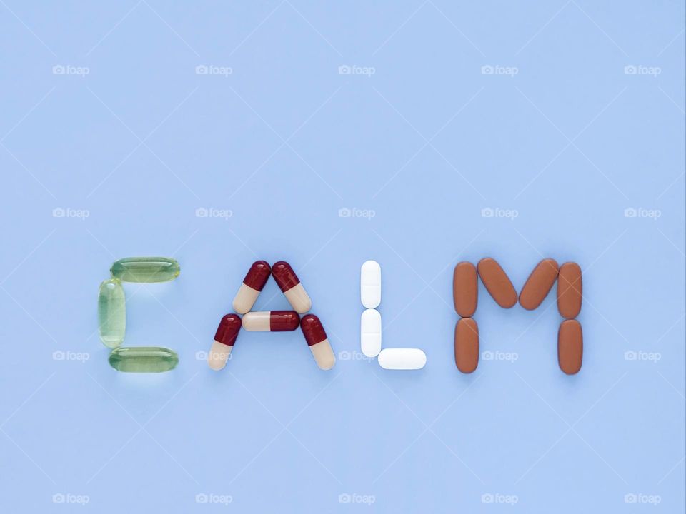 word calm with pills and capsules on blue background, mental health