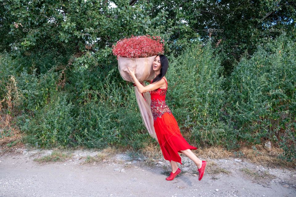 Woman Dances with a Large Bouquet of Red Flowers