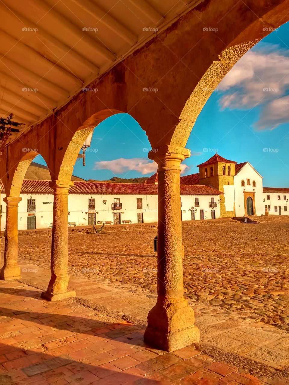 Arcos, columnas, sombras y contrastes en la plaza principal de Villa de Leyva Boyacá Colombia al atardecer. Arches, columns, shadows and contrasts in the main square of Villa de Leyva Boyacá Colombia at sunset. Vertical