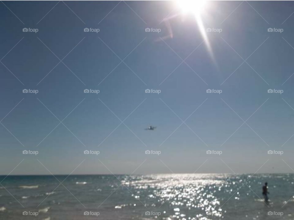 The sea,  a ray of sunshine  and an airplane.