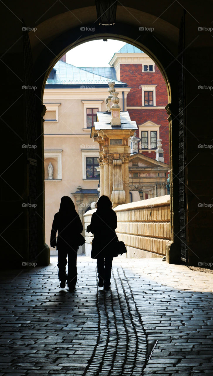 Silhouettes of two women walking through an archway 