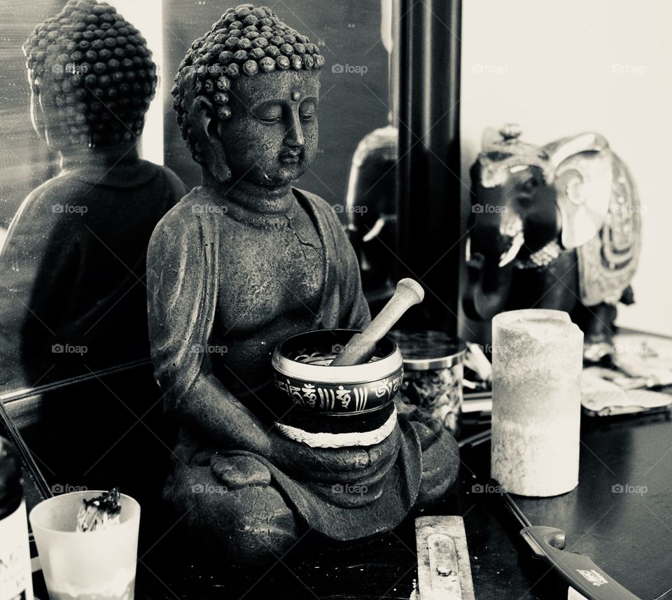 A Buddha and an elephant on a dresser with a candle 