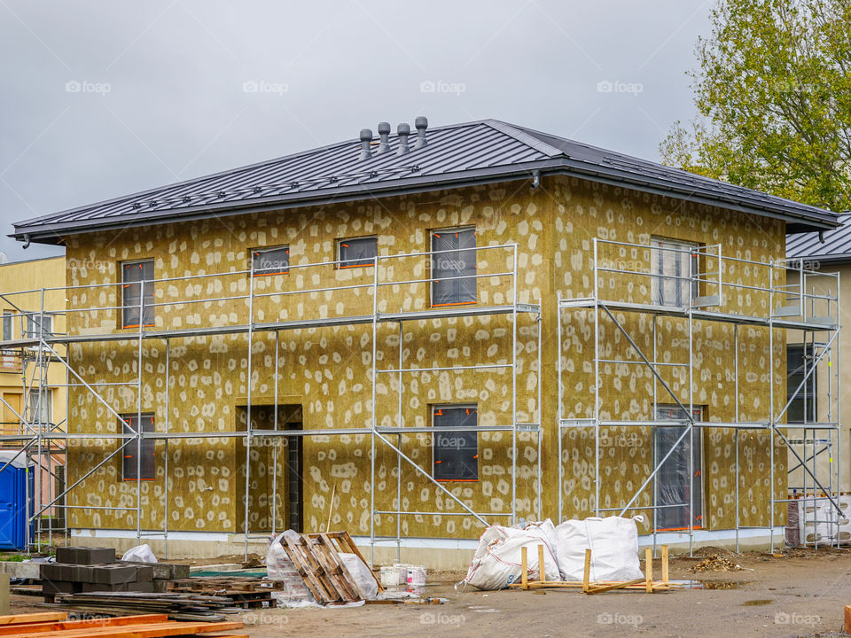 modern single family two store home under construction, enclosed with scaffolds, thermal insulation