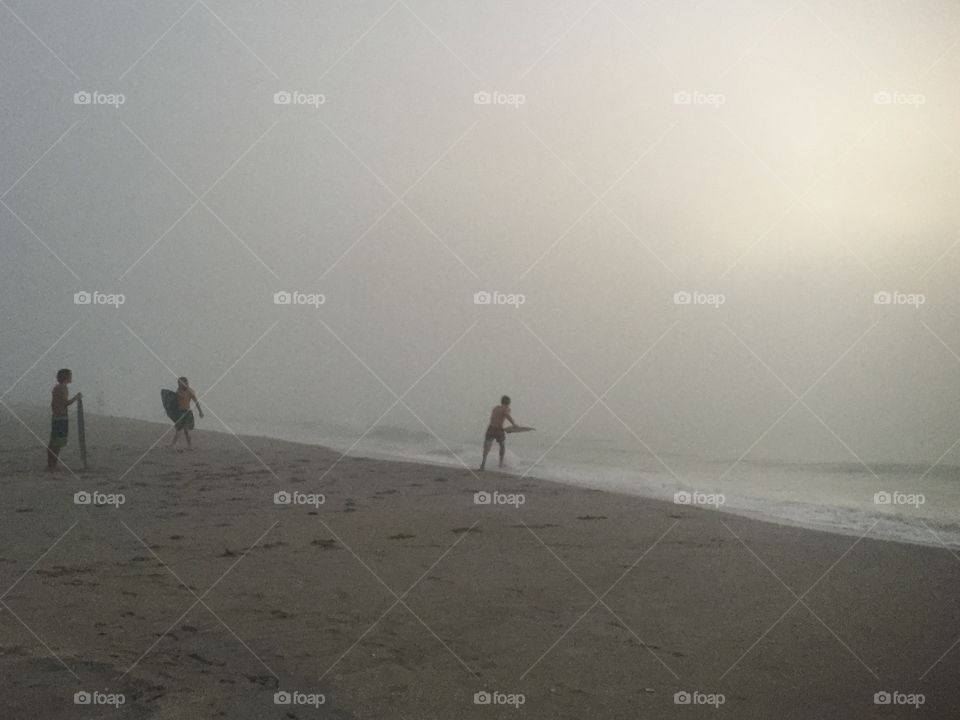 Skimboarders on a foggy morning 