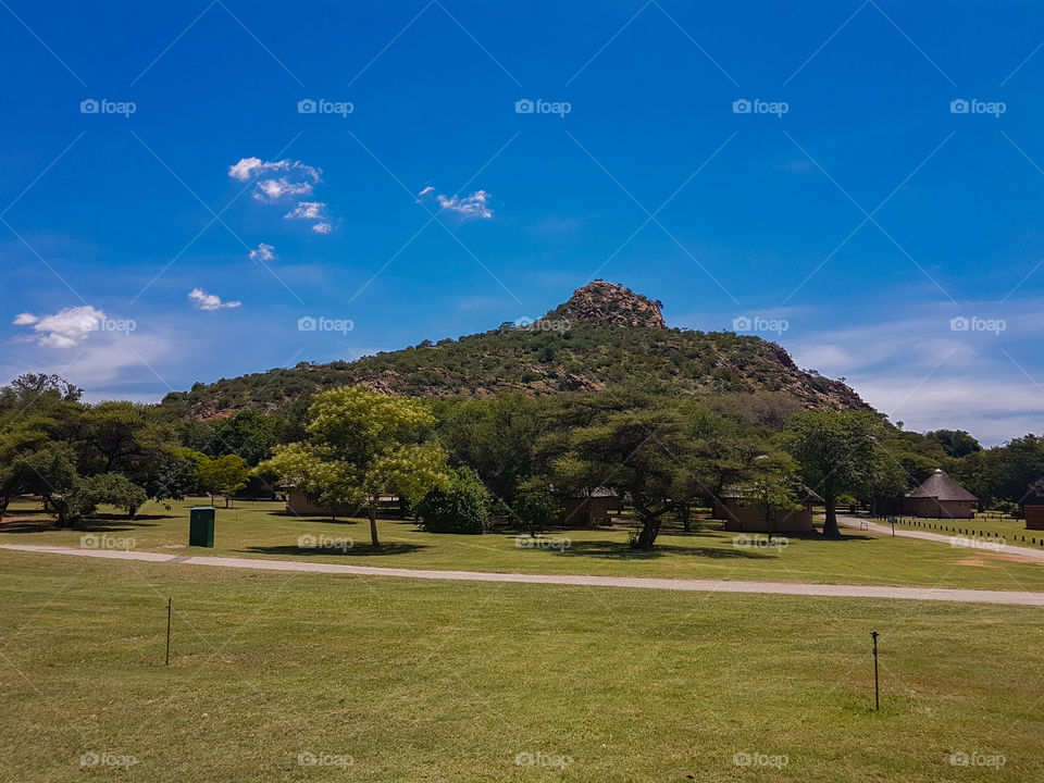mountain with blue skies and green grass in foreground