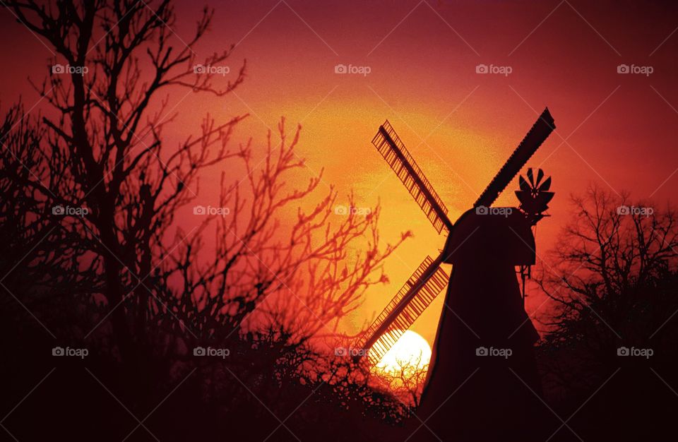 An English windmill silhouetted against the setting winter sun.