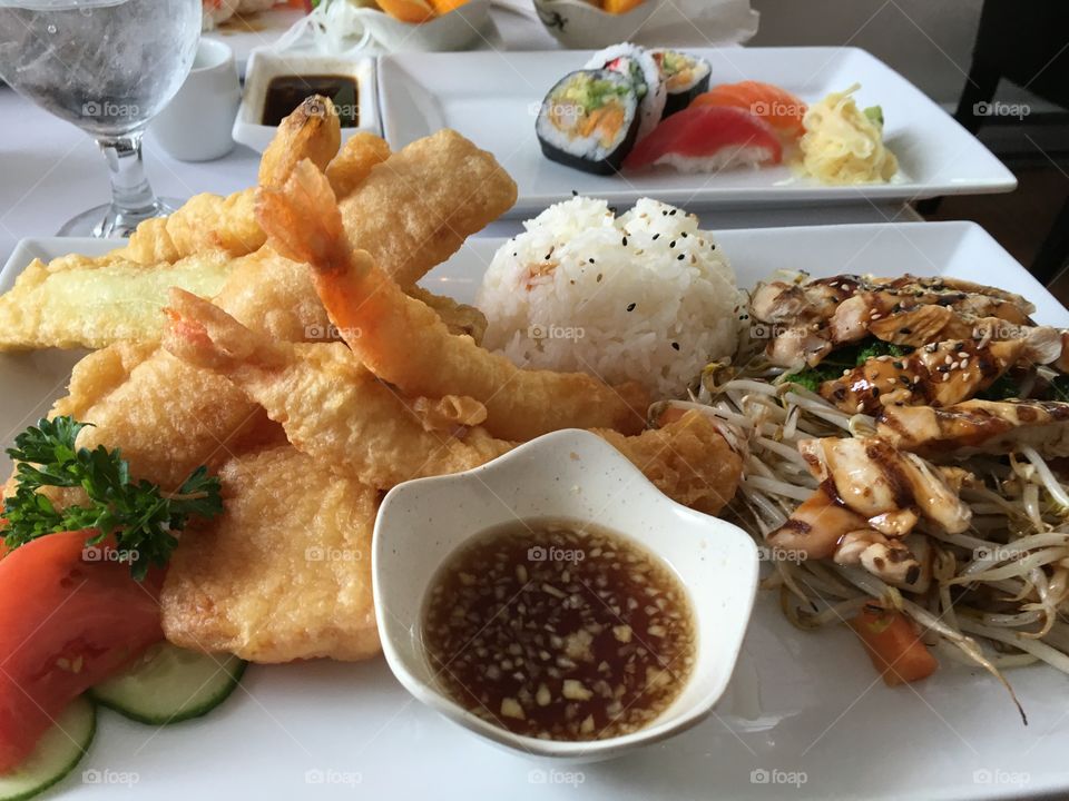 A Japanese feast of sushi, sashimi, tempura, seafood, veggies, artistically arranged and presented closeup 