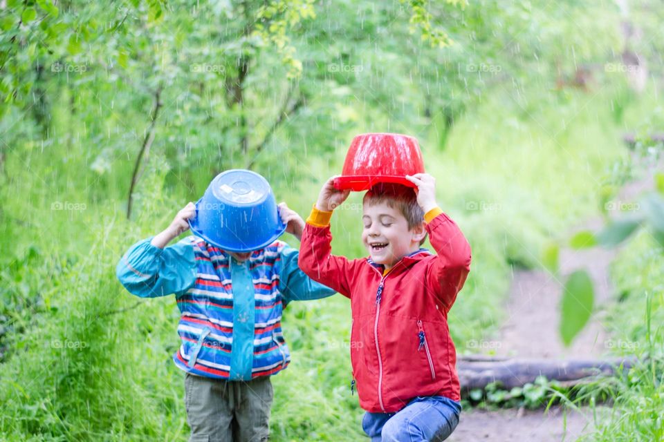 Children Playing in Rainy Spring Day with Buckets on Their Heads