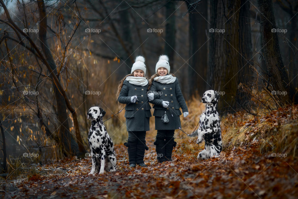 Twins girls with Dalmatian dogs in autumn park 