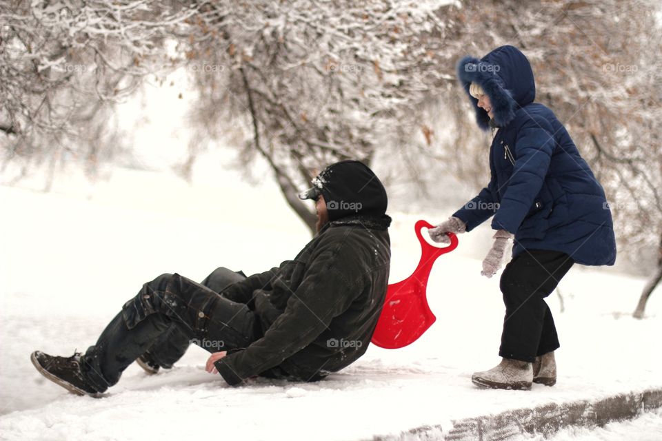 Girl with dad ride a hill in winter