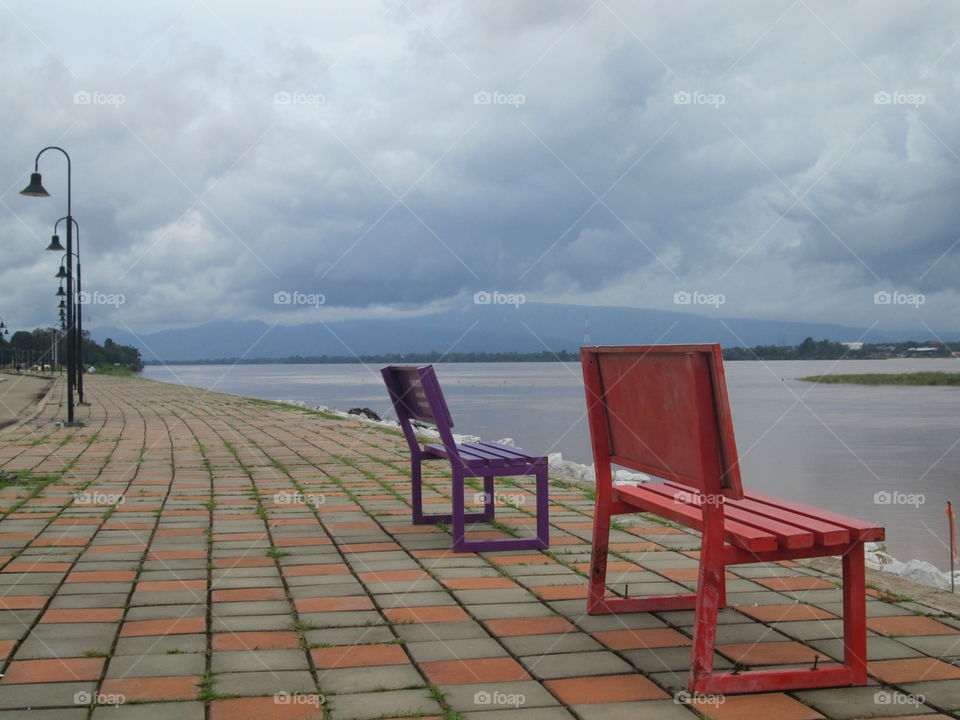 red and purple empty chair side of the river