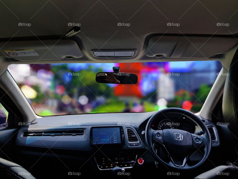 the view in car is parked, the view in the car, from the windshield of the car, from behind the wheel, only the color display looks like bokeh, full of beutiful color, the city street view looks blurry bokeh