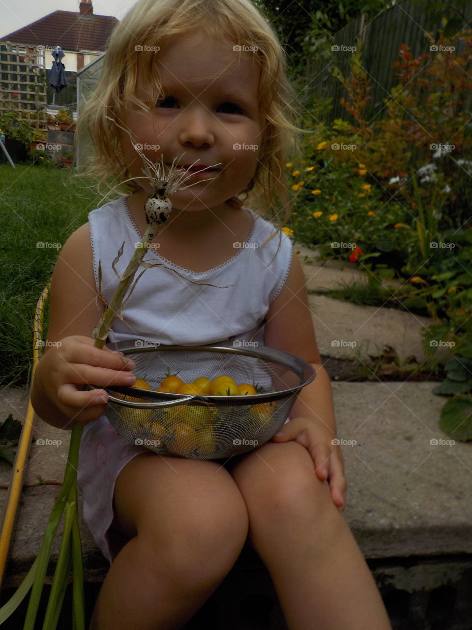 Little girl holding bowl with vegetables at garden