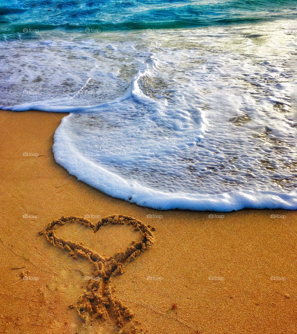 Heart shape on sand near surf  at beach