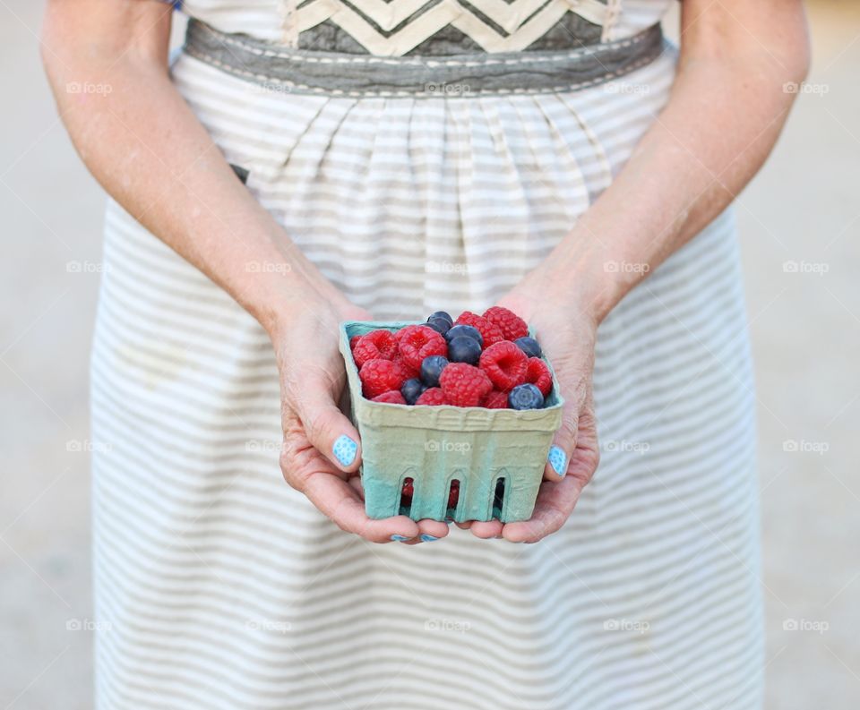 Woman holding raspberries and blueberries 