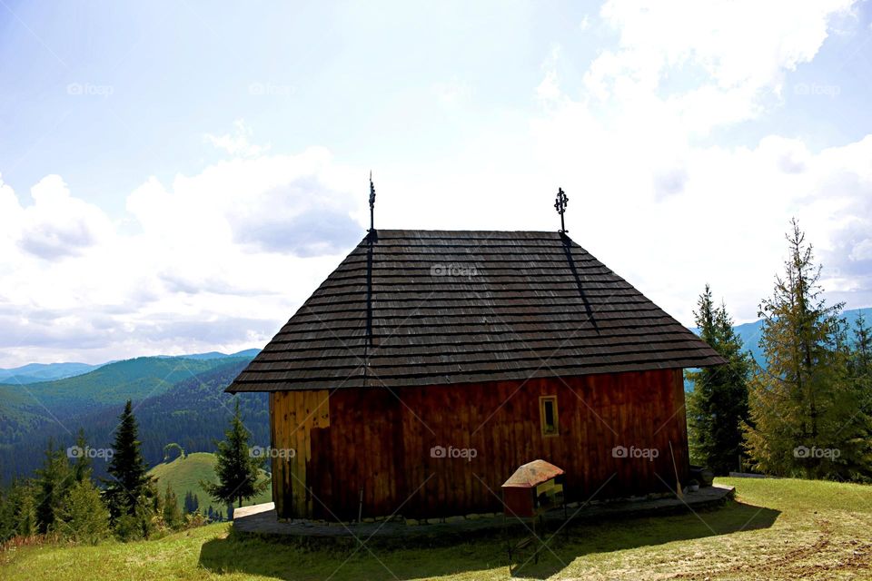 A small wooden monastery at the top of a hill,in front of the fortificated monastery of Sucevița.