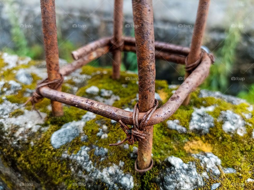 Close-up of rusty iron tied with wire, placed on a rock covered with moss