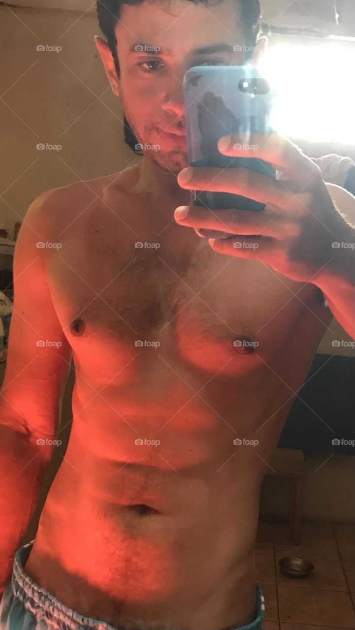 Strong man showing muscles in gym mirror, selfie