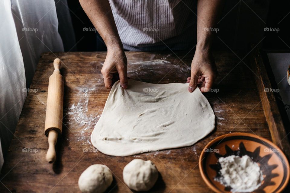 Man preparing a dough for bread, at home using his hands.