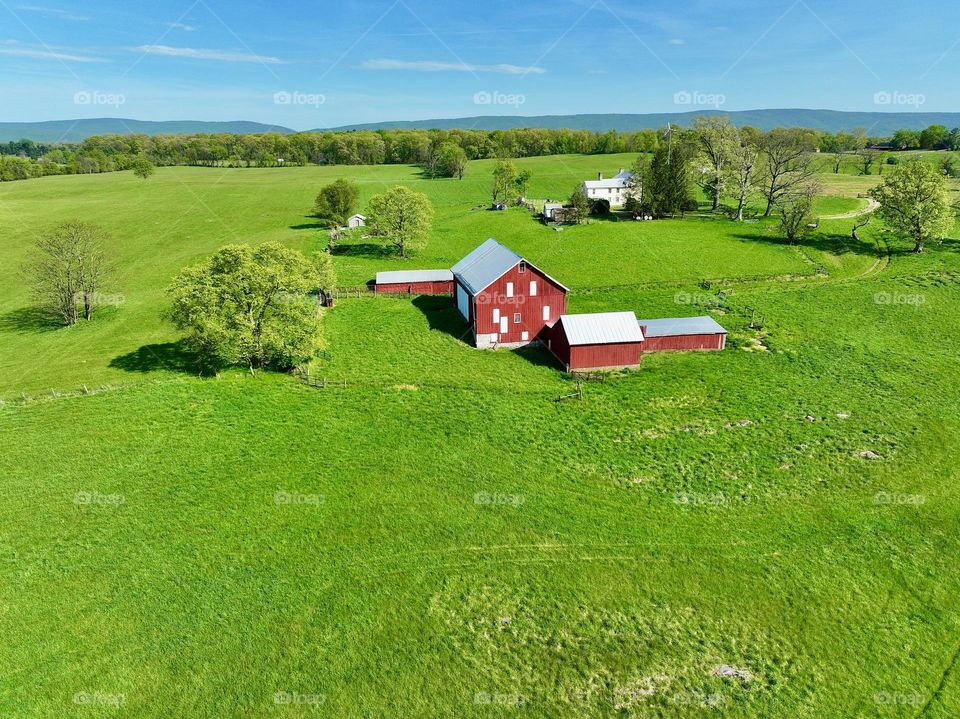 On a sunny spring day as the trees and flowers bloom a beautiful red barn sits amongst a sea of green on this farm 
