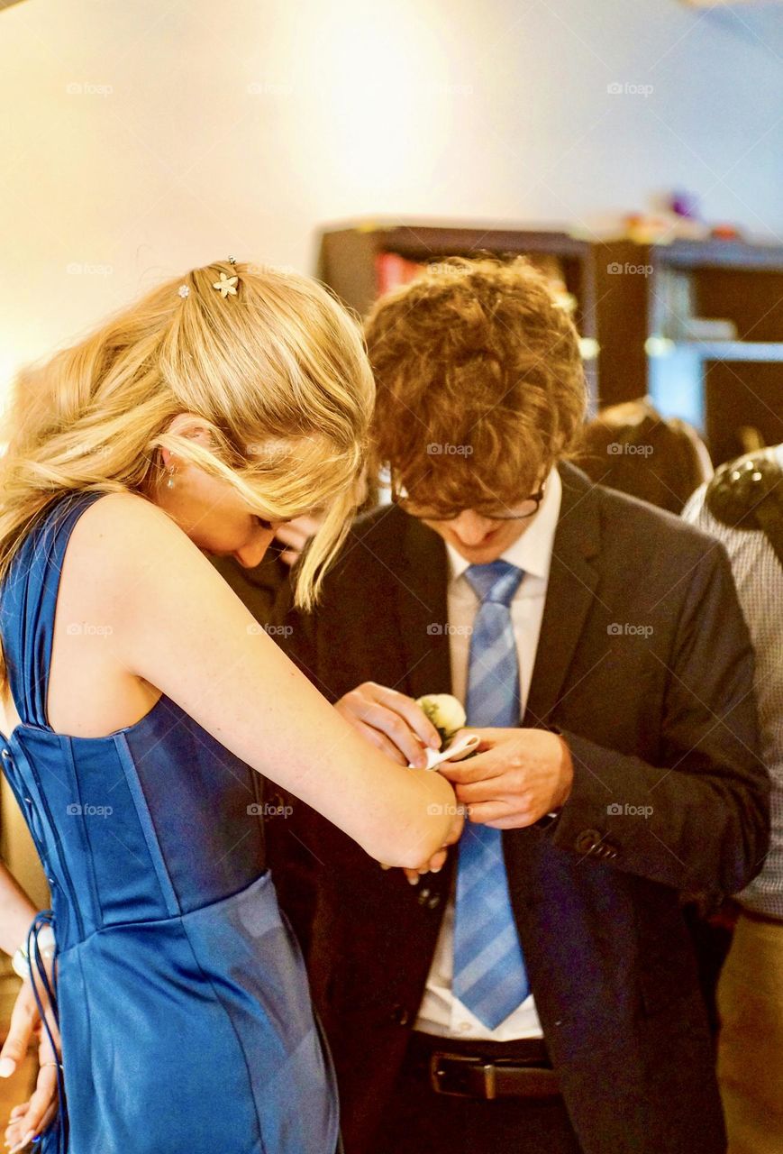 Graduation day, tying on the corsage.