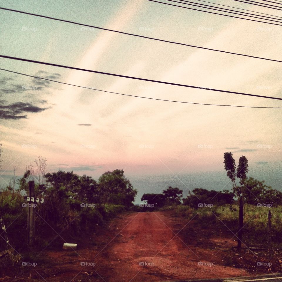 Uma estrada de terra perdida no meio do nada. Olha só a paisagem bucólica do amanhecer.