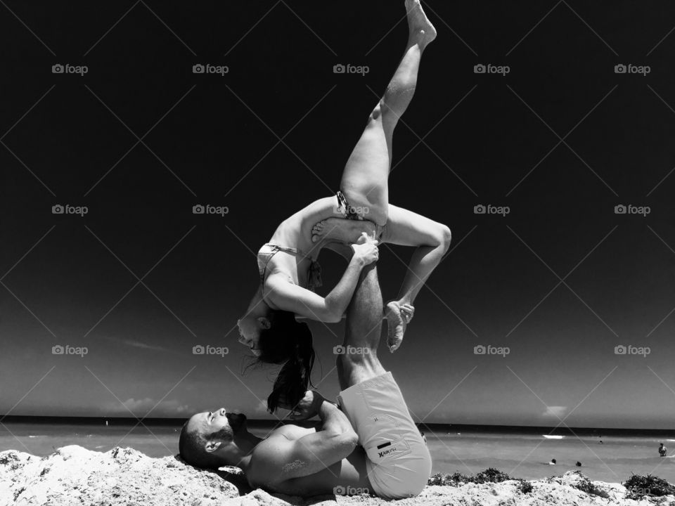 Couple doing acro yoga exercises at beach