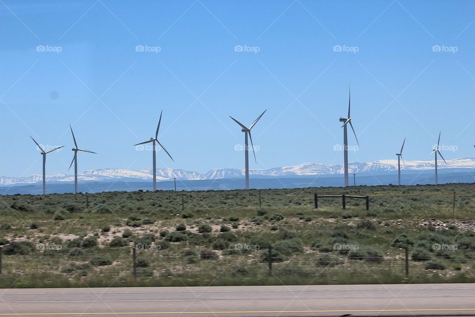 Wind mills among grassland in front of mountains 