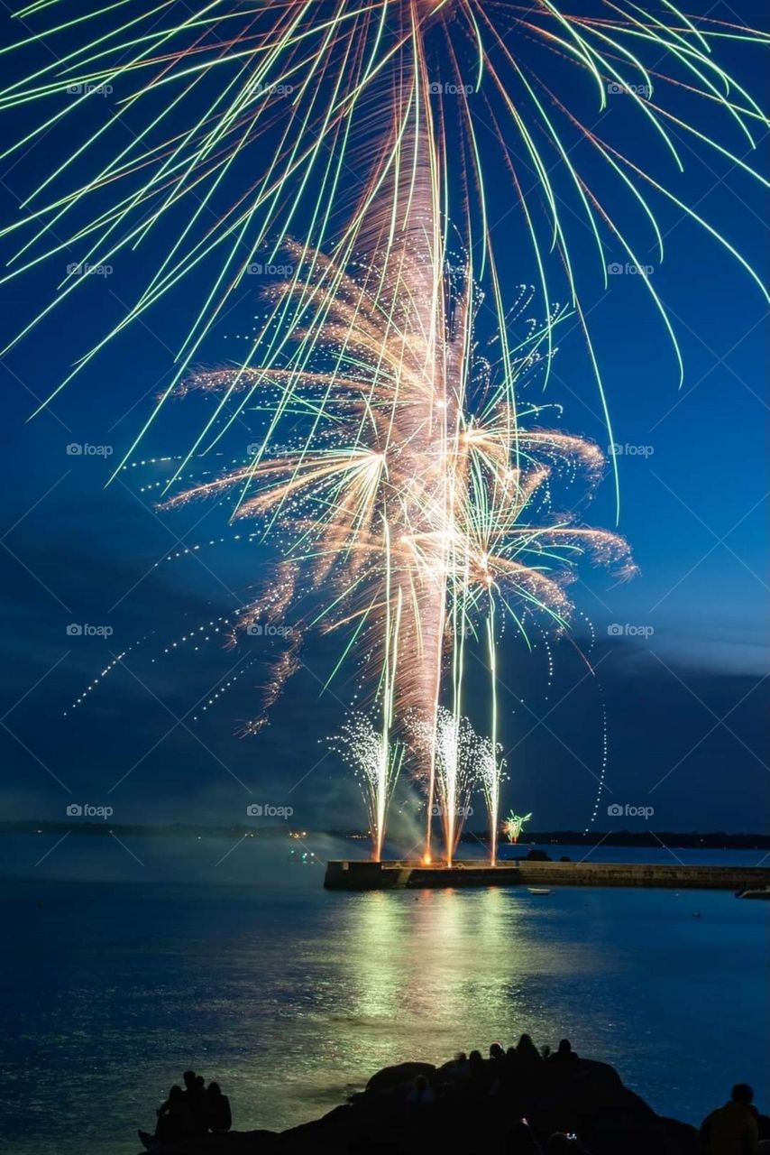 Fireworks on the harbour pier of Concarneau over the sea in an almost royal blue sky