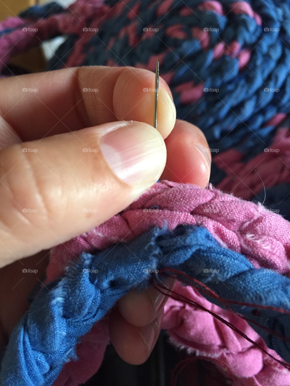 Sewing a homemade rag rug, blue and pink in colour
