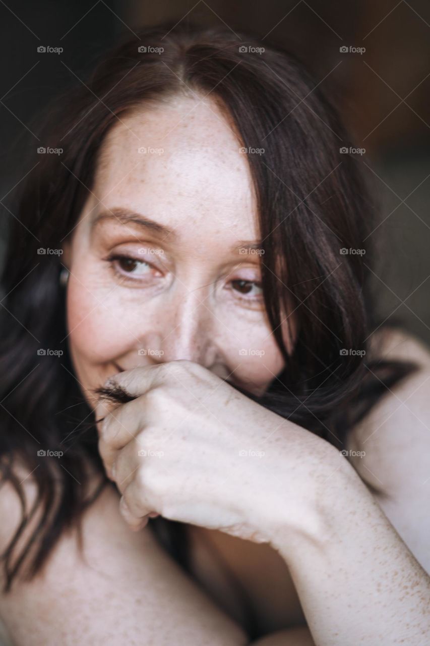 Adult brunette self loving forty years woman with natural skin with freckles and wrinkles at home 