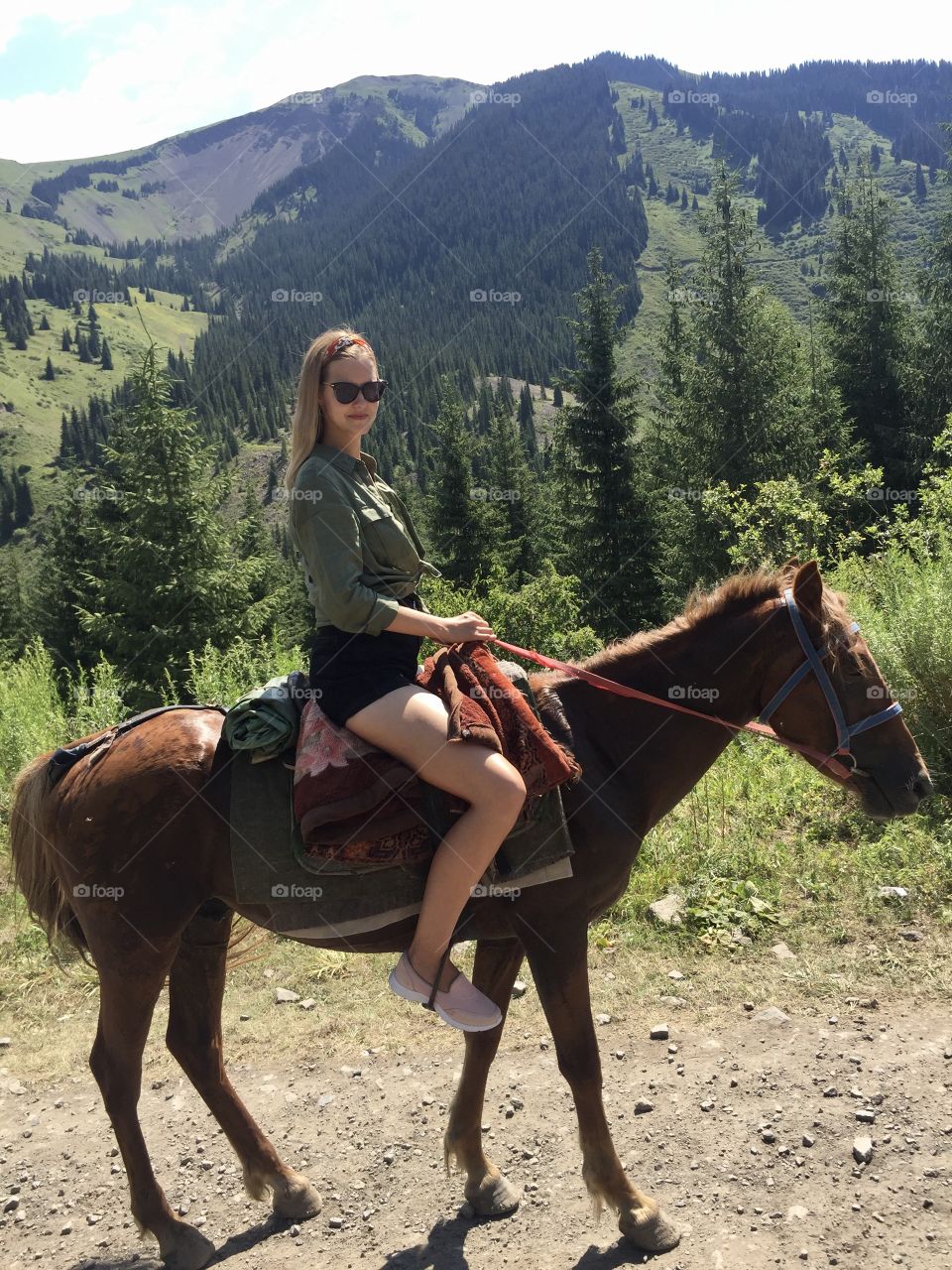 beautiful, slender, brave girl in dark sunglasses, European appearance on horseback conquers the mountains