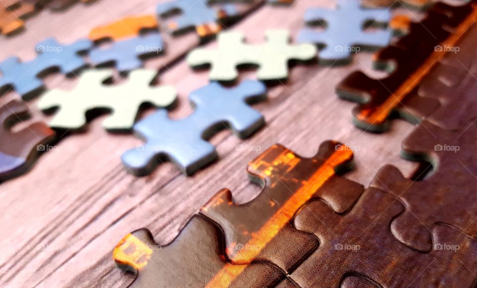 Pieces of a jigsaw puzzle on a  wooden table.