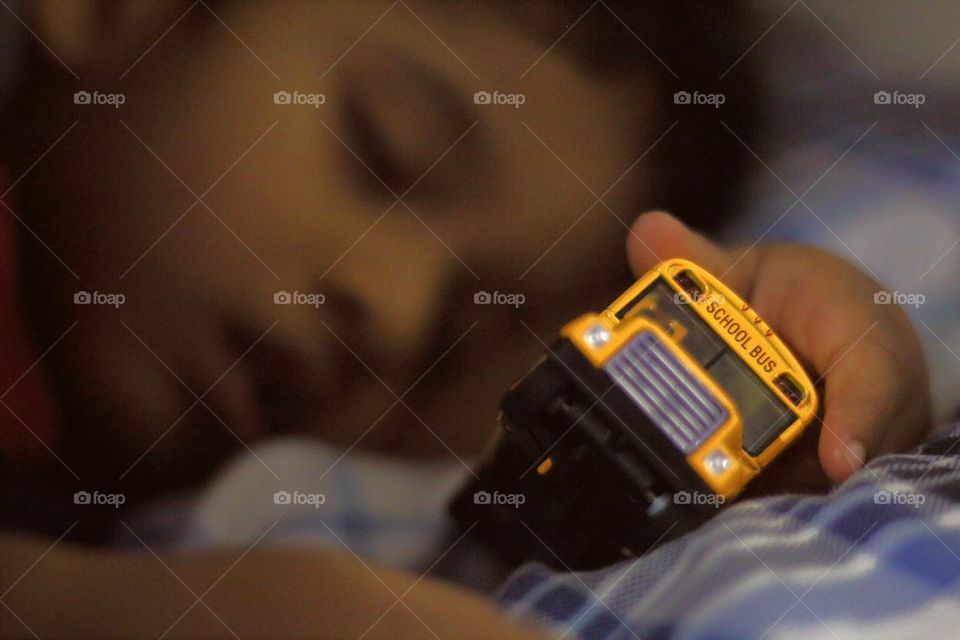 A boy sleeping with School Bus toy in his hand